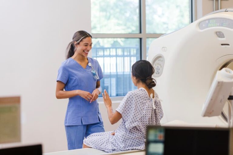 Imaging technician smiling with patient in front of machine