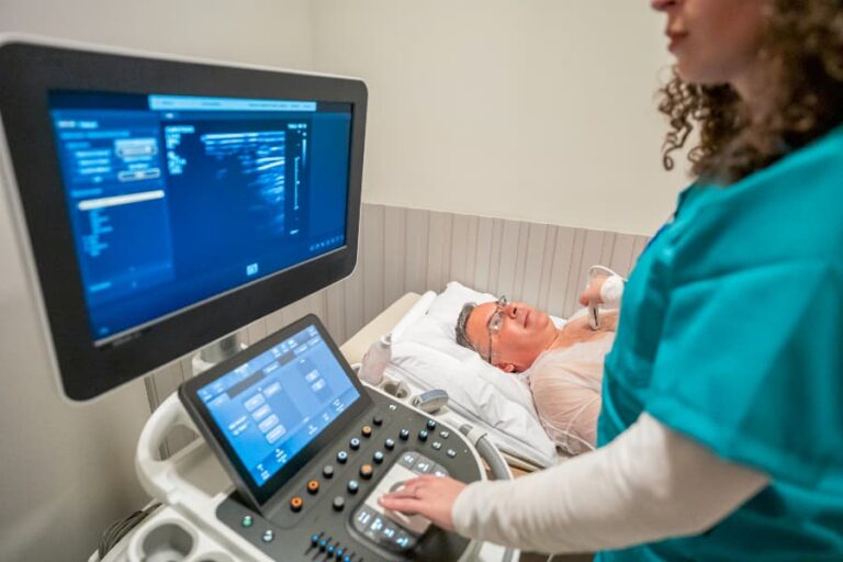 Patient laying on medical bed in exam room while echo technician performs ultrasound on heart